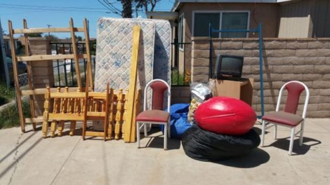 Mattress, chairs, and mixed household junk staged at a San Diego curb